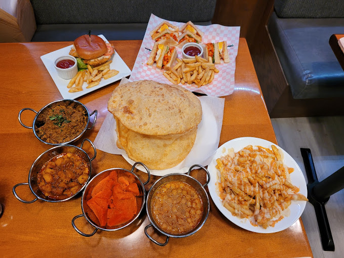 A variety of Pakistani and fast food dishes, including chole bhature, curries, fries, and sandwiches.