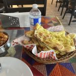 A basket of garlic naan with a side of spicy curry served at a restaurant