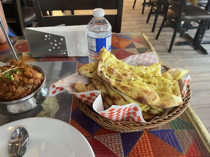 A basket of garlic naan with a side of spicy curry served at a restaurant