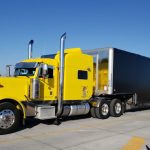 Bright yellow SSP truck with a black trailer, parked and ready for delivery.