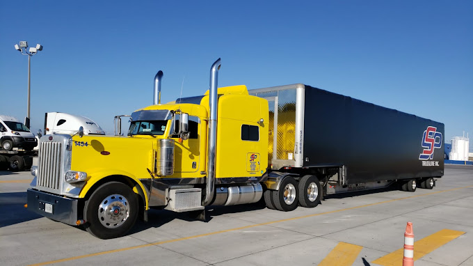 Bright yellow SSP truck with a black trailer, parked and ready for delivery.